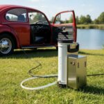 Aqua Peak 190 portable water pump connected to a car cigarette lighter, showcasing its compact design for easy outdoor use and travel.